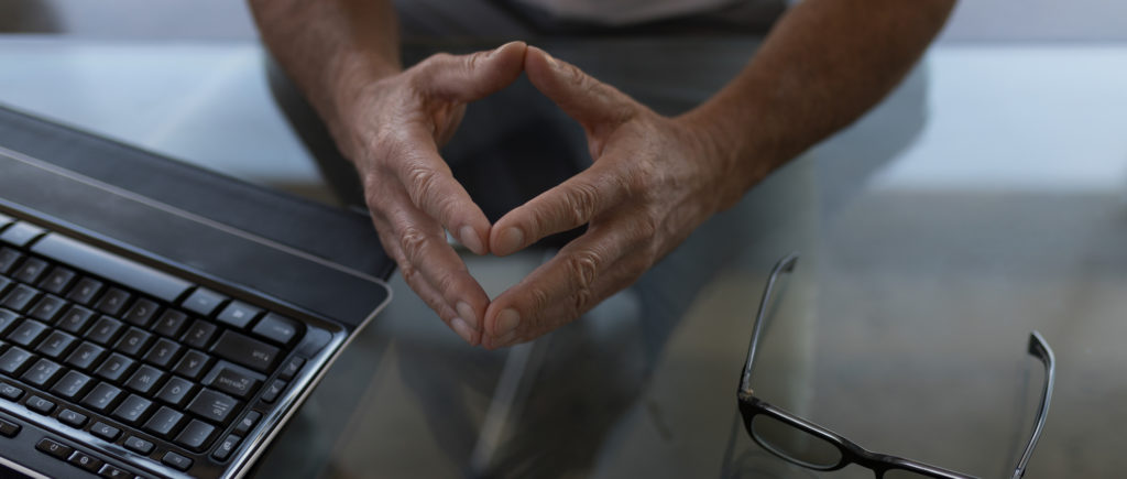 Male hands on glass desk by computer 
